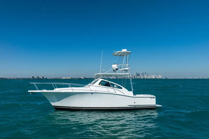 Slide: The Image of 2004 Luhrs 32 Open yacht on blue ocean with city skyline background. - 69