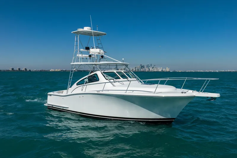 Slide: The Image of 2004 Luhrs 32 Open boat cruising on blue ocean with city skyline in background. - 72