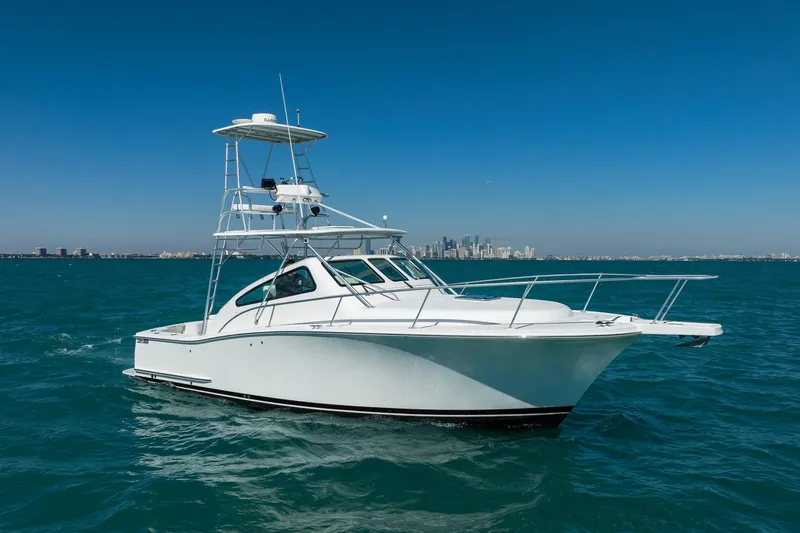 Slide: The Image of 2004 Luhrs 32 Open boat cruising on blue ocean with city skyline in background. - 73
