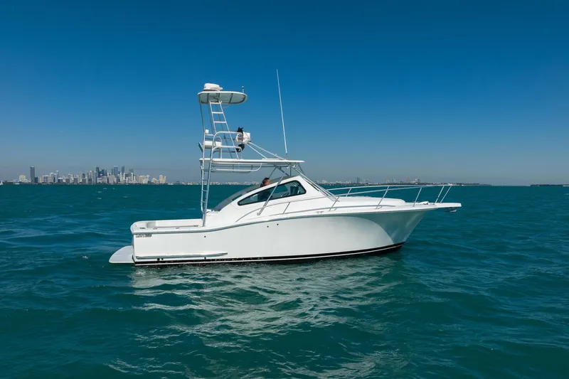 Slide: The Image of 2004 Luhrs 32 Open boat on blue ocean with city skyline in background. - 74