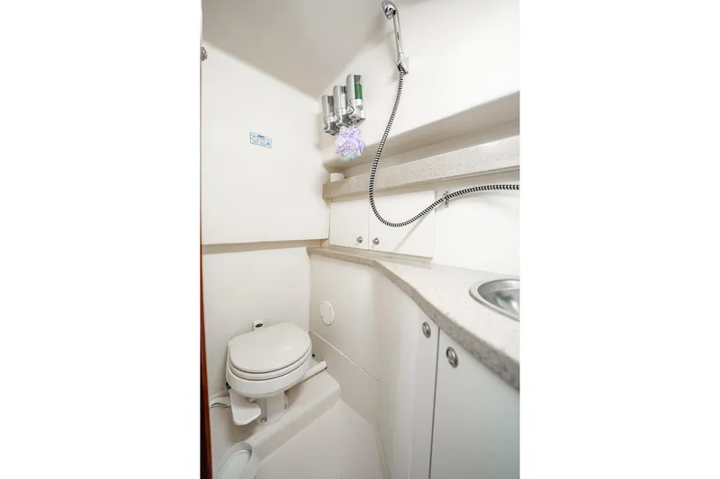 Slide: The Image of 2004 Luhrs 32 Open boat bathroom with toilet, sink, and showerhead. - 81
