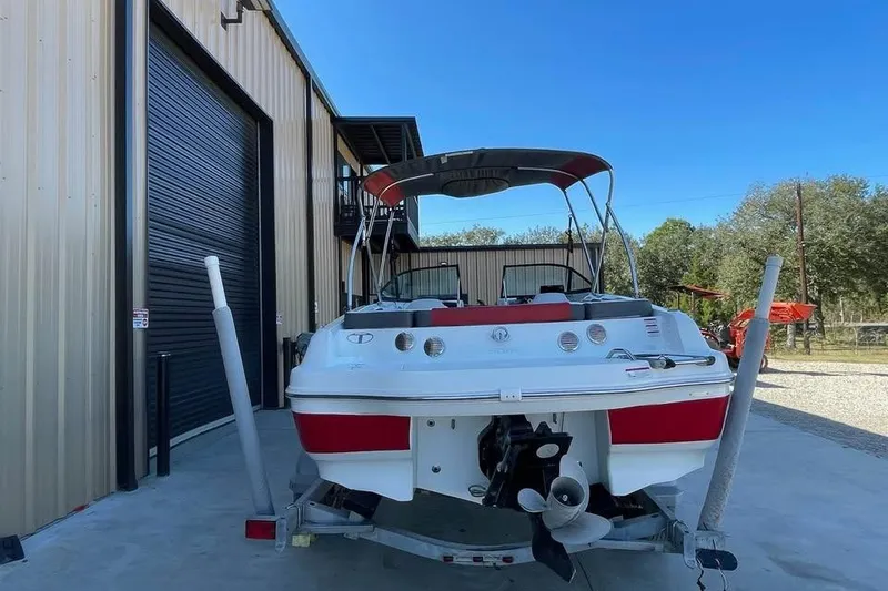 Slide: The Image of 2018 Tahoe 500 TF boat on trailer near a metal building, clear blue sky. - 3