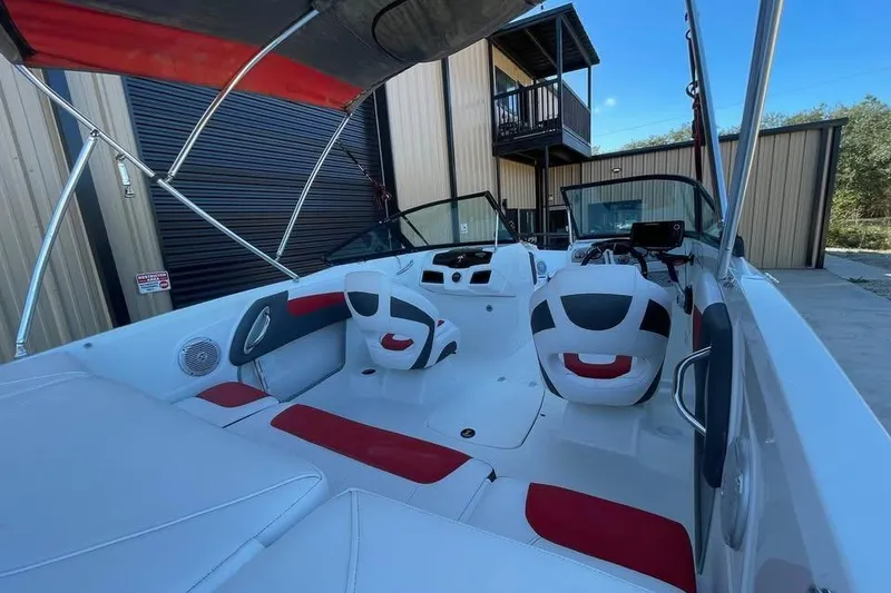 Slide: The Image of 2018 Tahoe 500 TF boat interior with red and white seating, parked near a building. - 8