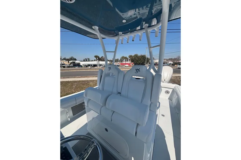 Slide: The Image of 2026 Yellowfin 36 Offshore boat with white seating and steering wheel, parked outdoors. - 12