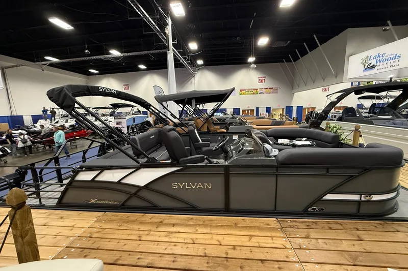The Image of 2026 Sylvan Mirage X X3 CLZ DH pontoon boat displayed indoors at a marine exhibition. - 0