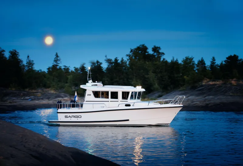 Slide: The Image of 2024 Sargo 28 boat cruising on a serene lake at dusk. - 1