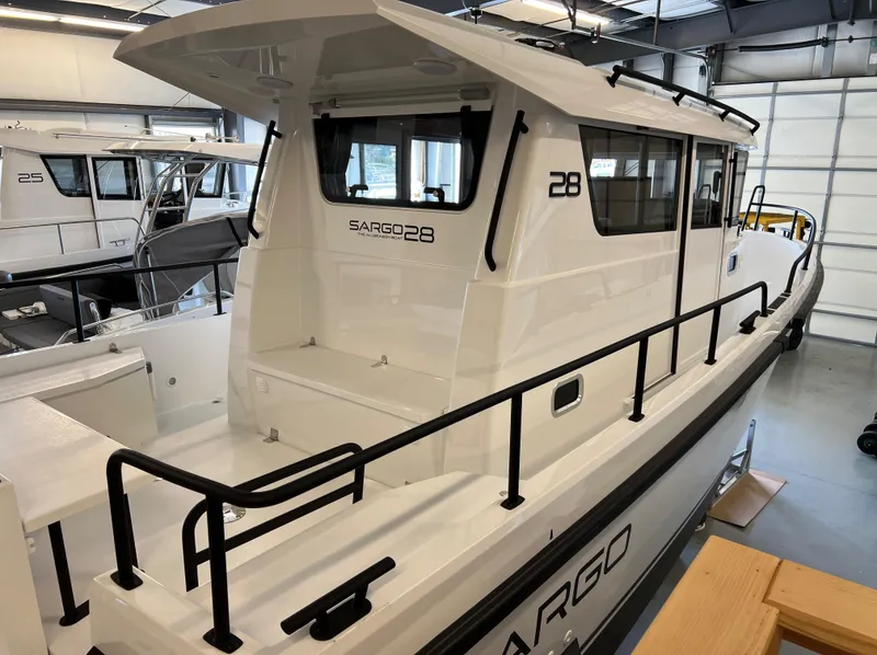 Slide: The Image of 2024 Sargo 28 boat in showroom, rear view with black railings and white exterior. - 3