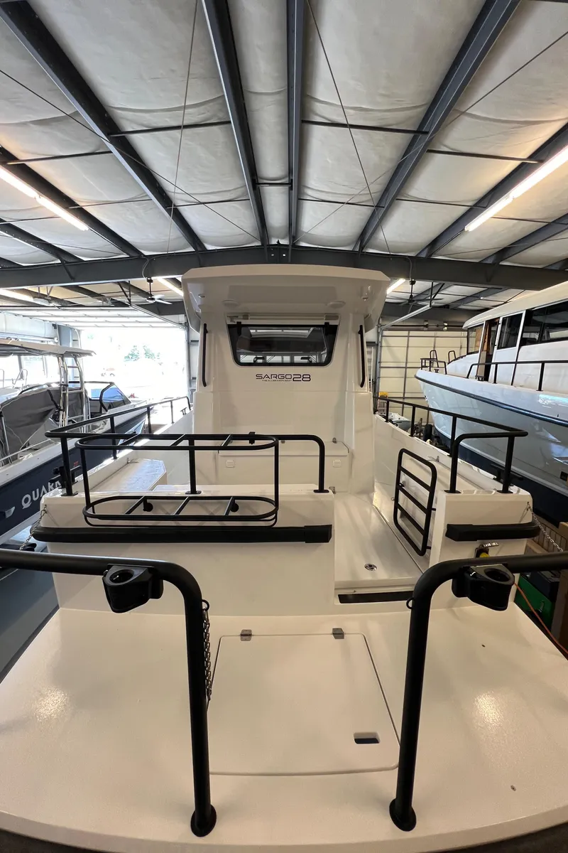 Slide: The Image of 2024 Sargo 28 boat in a showroom, rear view with railings and cabin entrance. - 6