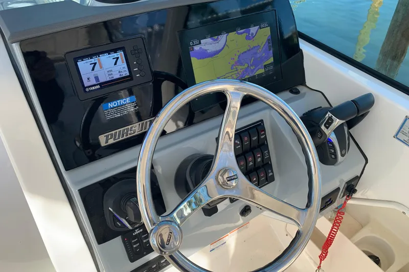 Slide: The Image of 2023 Pursuit DC 266 Dual Console boat dashboard with steering wheel and navigation displays. - 11