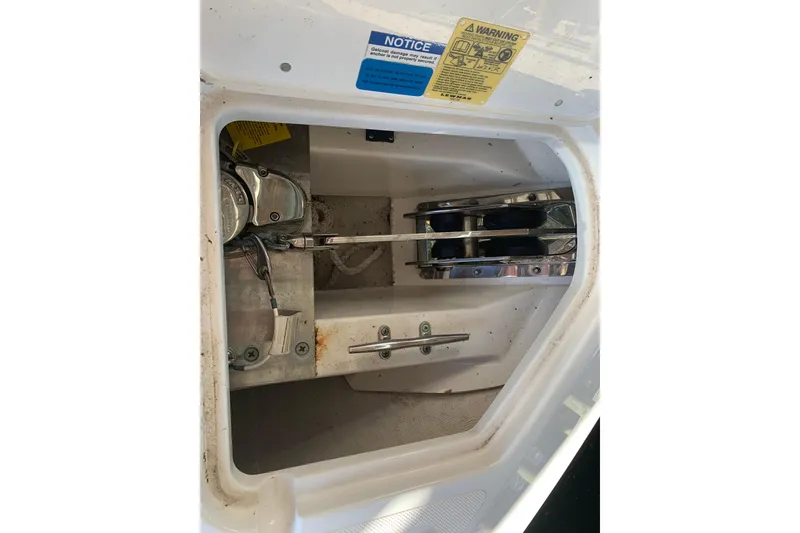 Slide: The Image of 2023 Pursuit DC 266 Dual Console anchor compartment with mechanical components and warning labels. - 17
