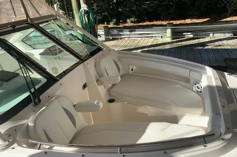 Slide: The Image of 2023 Pursuit DC 266 Dual Console boat interior with white seating and dock background. - 18