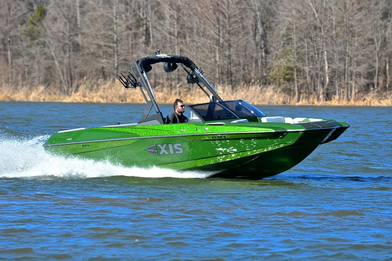 The Image of 2022 Axis A22 boat cruising on a lake with a forested background. - 1