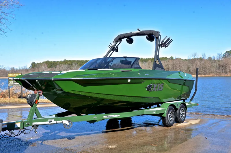 Slide: The Image of 2022 Axis A22 green boat on trailer by a lake under clear blue sky. - 10