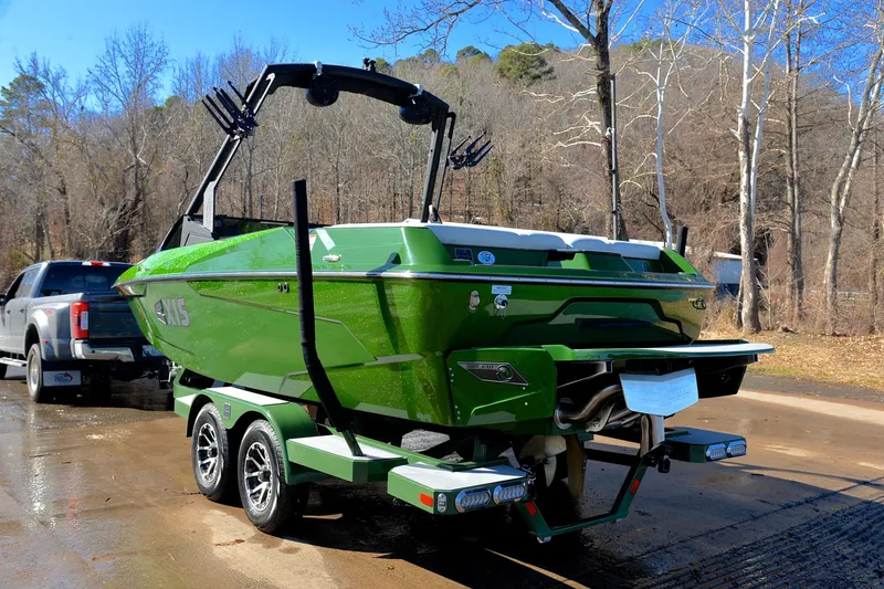 Slide: The Image of 2022 Axis A22 green boat on trailer, parked near forested area. - 12