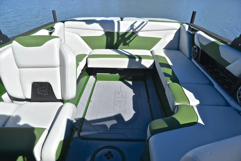 Slide: The Image of 2022 Axis A22 boat interior with green and white seating, on a calm lake. - 22