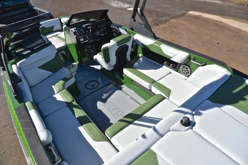 Slide: The Image of 2022 Axis A22 boat interior with green and white seating, steering console, and speakers. - 23