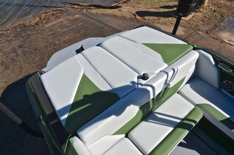 Slide: The Image of 2022 Axis A22 boat interior with green and white seating at a lakeside dock. - 24