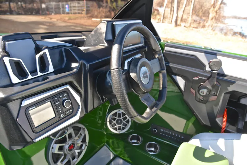 Slide: The Image of 2022 Axis A22 boat interior with steering wheel, audio controls, and green accents. - 28