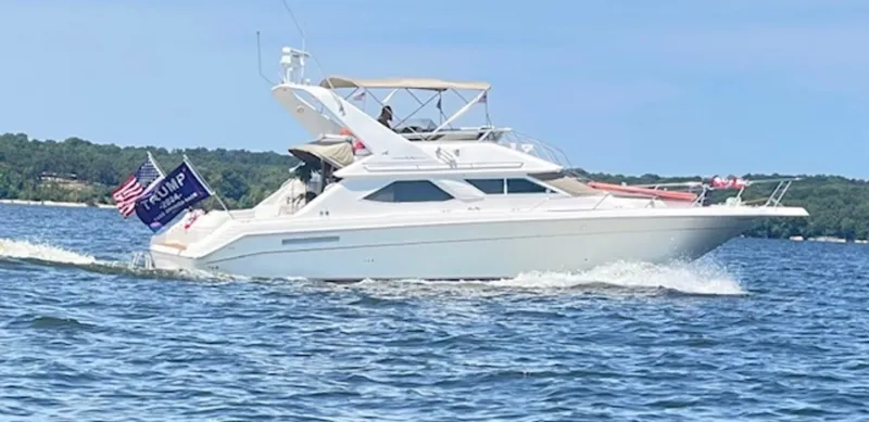 The Image of 1996 Sea Ray 440 Express Bridge on water with flags. - 0