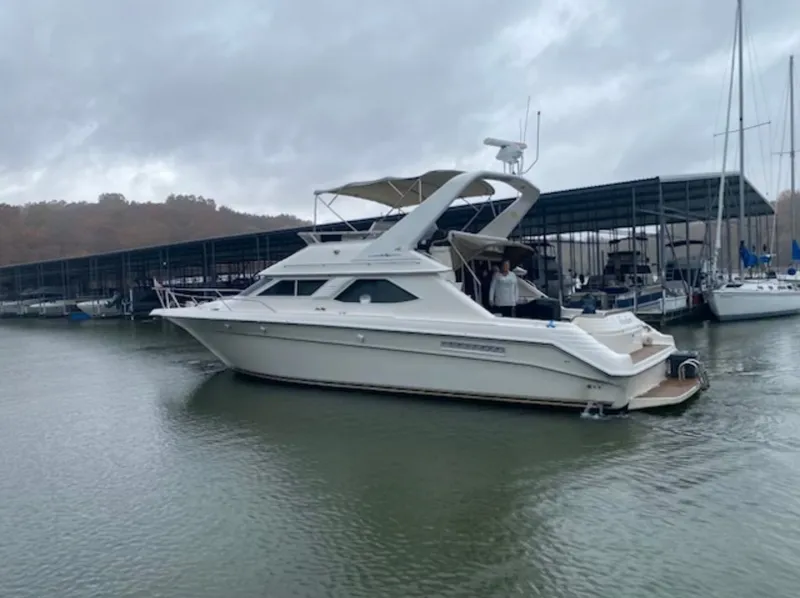 Slide: The Image of 1996 Sea Ray 440 Express Bridge docked under cloudy skies. - 1
