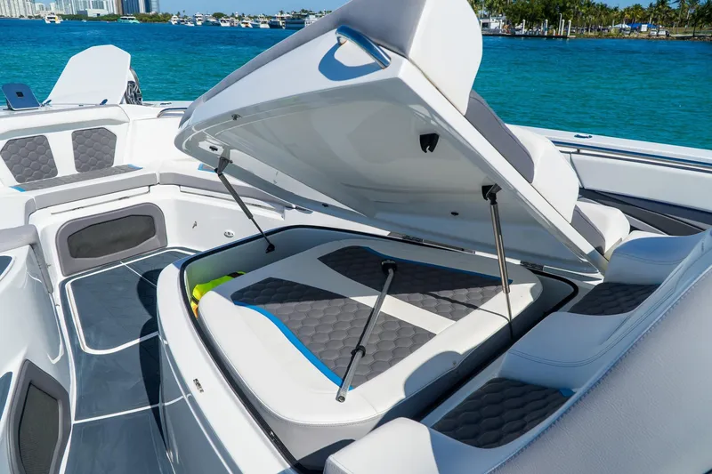 Slide: The Image of 2023 MTI 50v boat interior with open storage compartment, featuring sleek seating and ocean backdrop. - 29