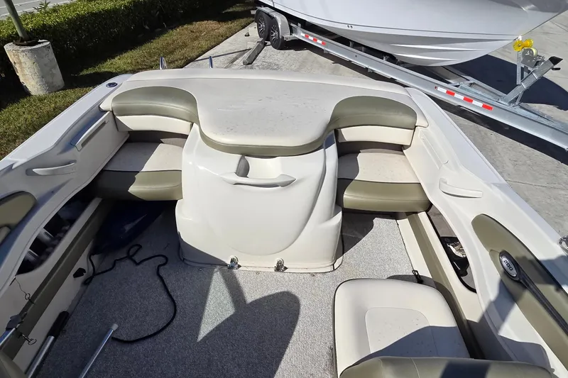 Slide: The Image of 2004 Sea Ray 200 Sport boat interior with cushioned seating and carpeted floor. - 10