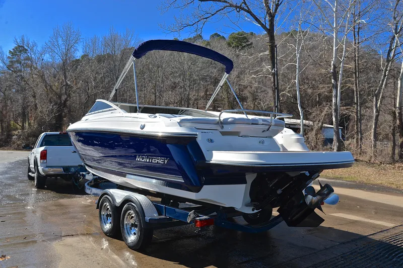 Slide: The Image of 2011 Monterey 234FS boat on trailer, parked near trees and a white truck. - 11