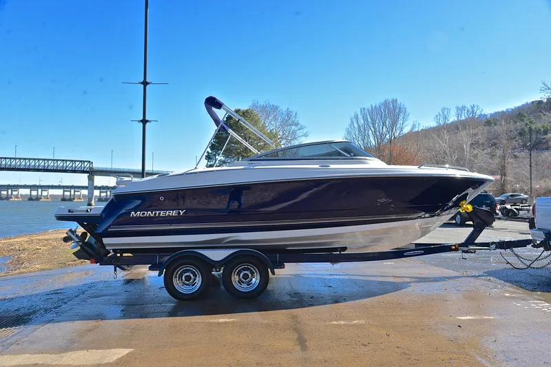 Slide: The Image of 2011 Monterey 234FS boat on trailer by riverside, clear blue sky background. - 14