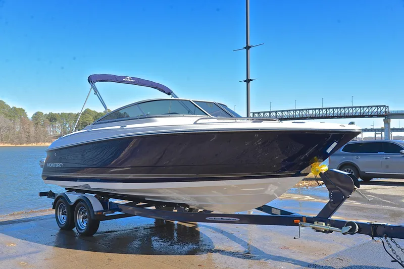Slide: The Image of 2011 Monterey 234FS boat on trailer by a lake under clear blue sky. - 15
