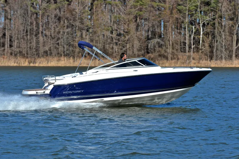 Slide: The Image of 2011 Monterey 234FS boat cruising on a lake with forested background. - 2