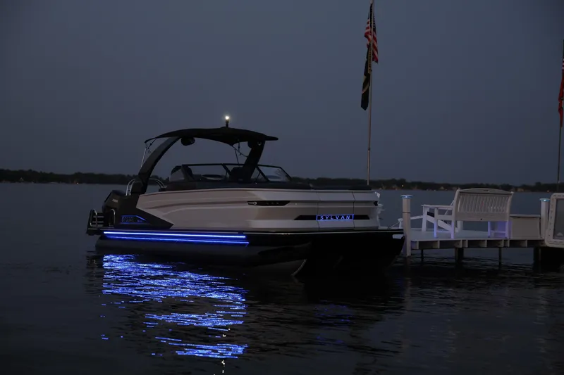 Slide: The Image of 2025 Sylvan M5 CLZ DC boat with blue LED lights docked at night. - 19