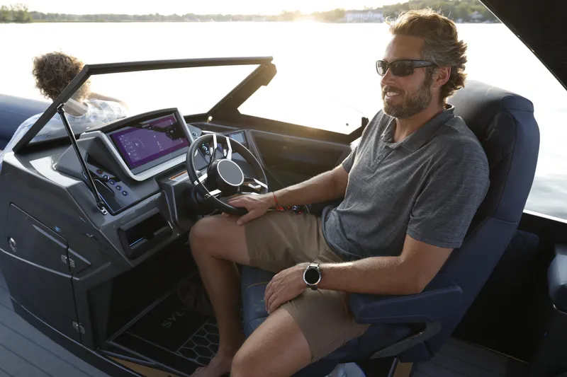 Slide: The Image of Man piloting 2025 Sylvan M5 CLZ DC boat, enjoying a sunny day on the water. - 22