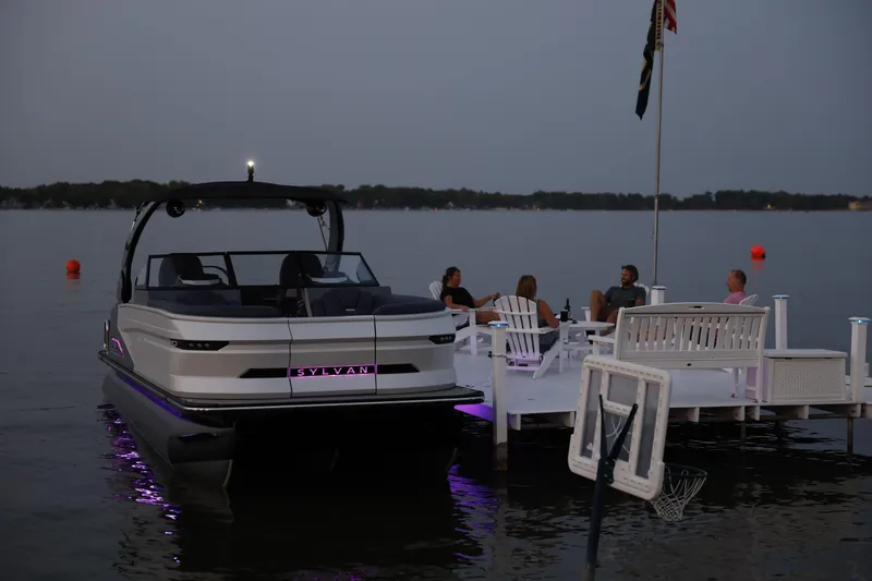 Slide: The Image of 2025 Sylvan M5 CLZ DC pontoon boat docked at sunset with people relaxing nearby. - 4
