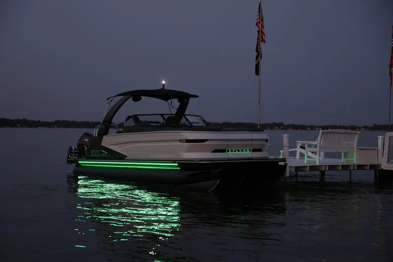 Slide: The Image of 2025 Sylvan M5 CLZ DC boat with green lights docked at night. - 9