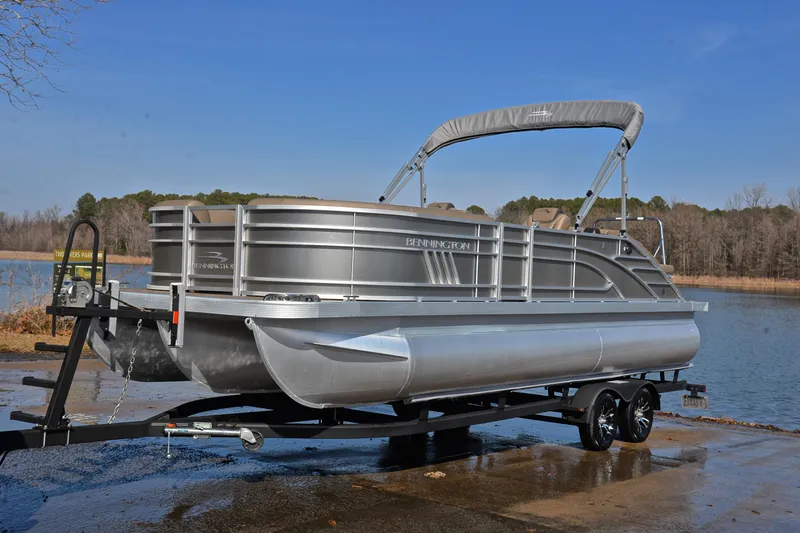 Slide: The Image of 2023 Bennington L23 pontoon boat on trailer by a lake. - 10