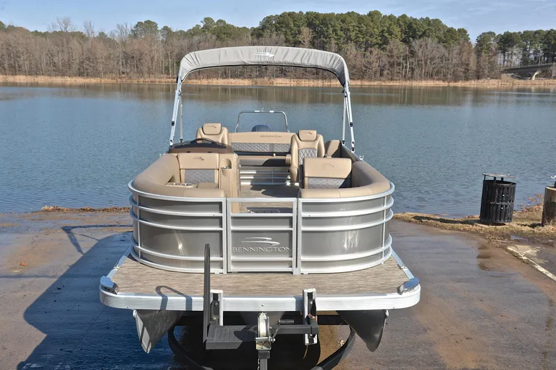Slide: The Image of 2023 Bennington L23 pontoon boat on a trailer by a serene lake. - 17