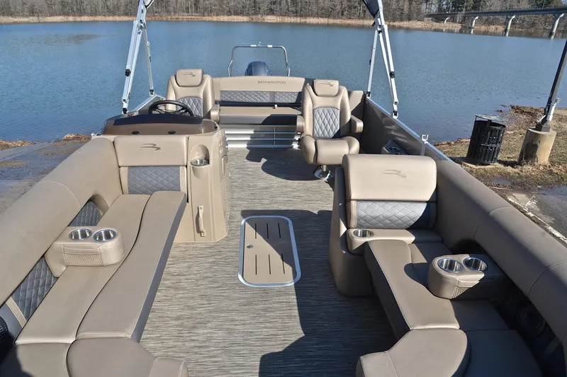 Slide: The Image of 2023 Bennington L23 pontoon boat interior with luxurious seating and cup holders by a serene lake. - 20