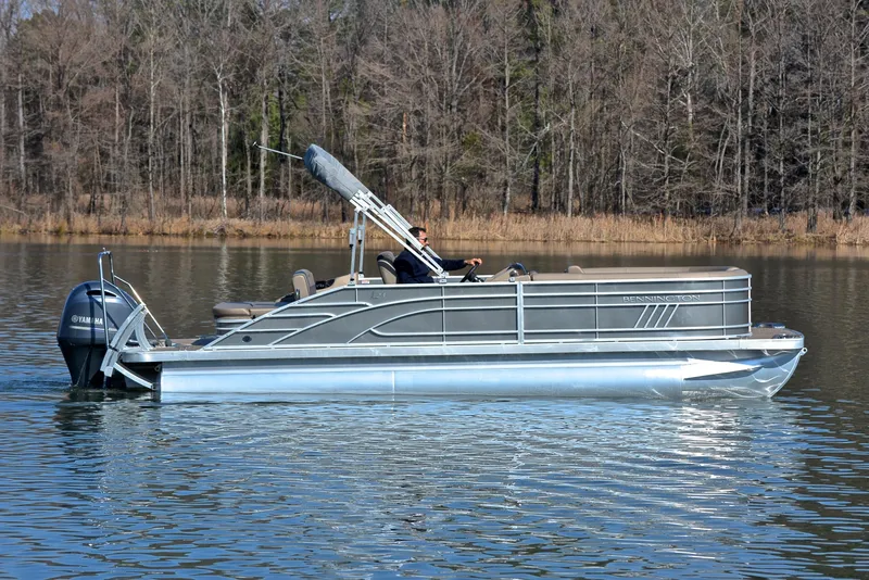 Slide: The Image of 2023 Bennington L23 pontoon boat cruising on a calm lake. - 6