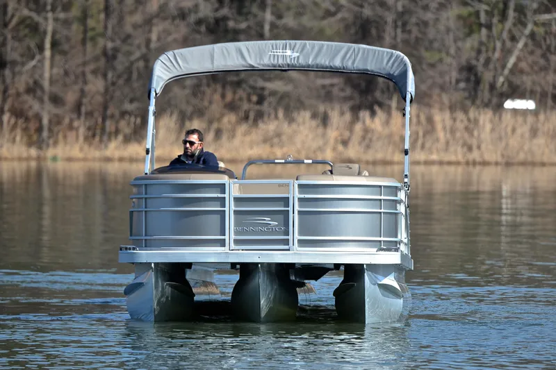 Slide: The Image of 2023 Bennington L23 pontoon boat cruising on a calm lake. - 9