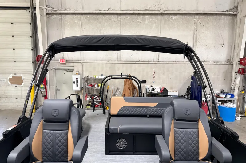 Slide: The Image of 2026 Godfrey Sweetwater 22' Tritoon interior with stylish seating and canopy in a workshop. - 43