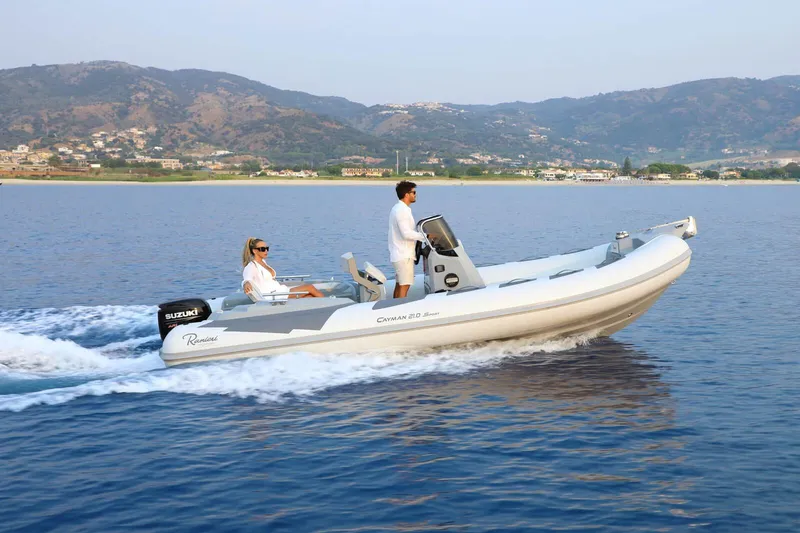 Slide: The Image of 2026 Ranieri Cayman 21.0 Sport boat cruising on calm waters with scenic mountain backdrop. - 5