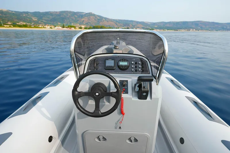 Slide: The Image of 2026 Ranieri Cayman 21.0 Sport boat dashboard with steering wheel on calm water. - 7