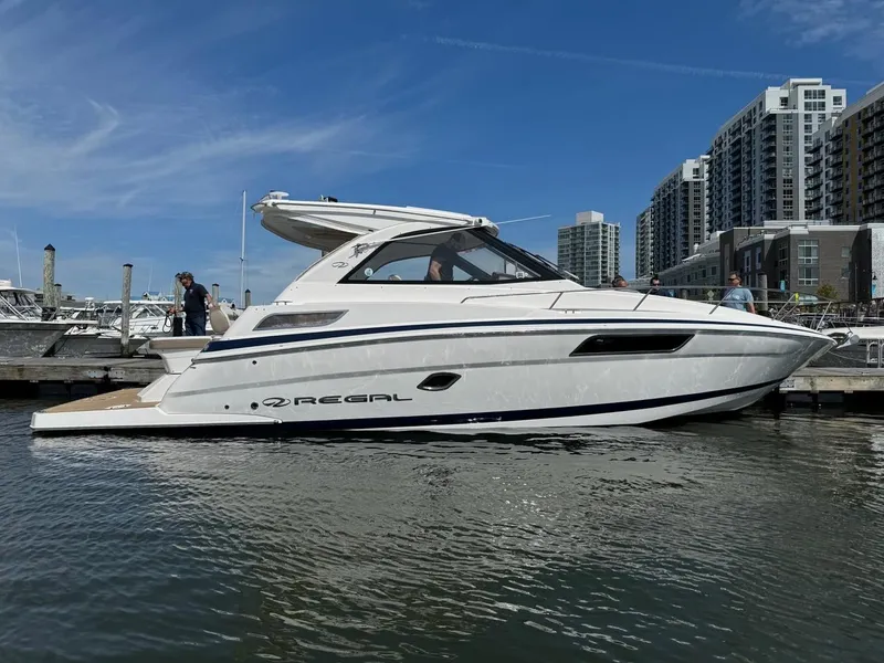 The Image of 2016 Regal 35 Sport Coupe yacht docked in marina, modern buildings in background. - 0