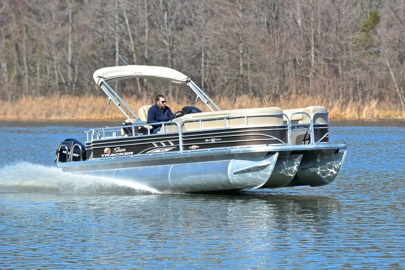 The Image of 2023 Sun Tracker SportFish 22 XP3 pontoon boat cruising on a lake. - 1