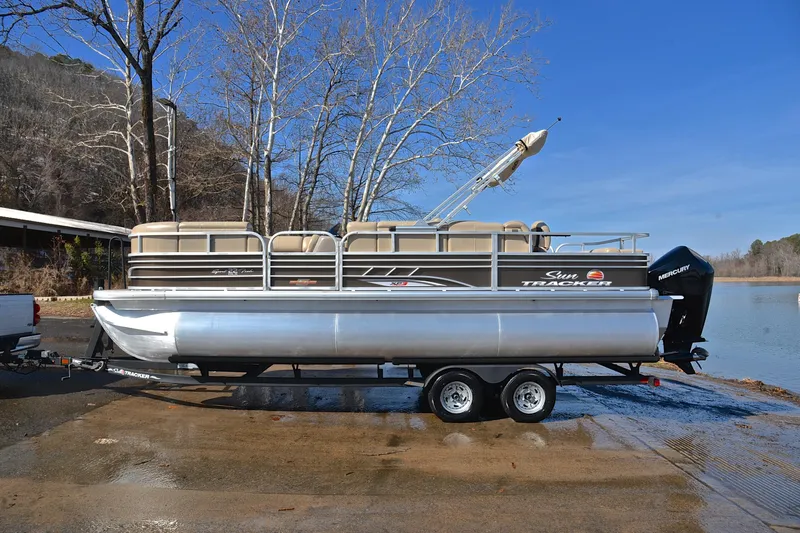Slide: The Image of 2023 Sun Tracker SportFish 22 XP3 pontoon boat on trailer by a lake. - 11
