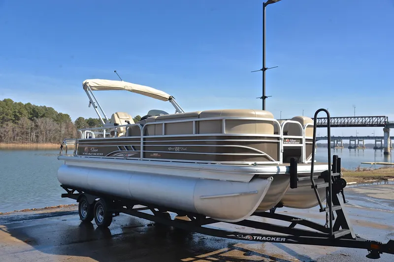 Slide: The Image of 2023 Sun Tracker SportFish 22 XP3 pontoon boat on trailer by a lake. - 16
