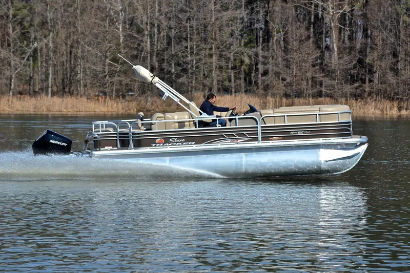 Slide: The Image of 2023 Sun Tracker SportFish 22 XP3 pontoon boat cruising on a lake. - 3