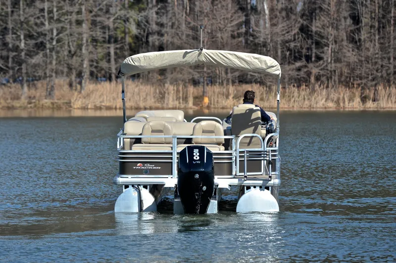 Slide: The Image of 2023 Sun Tracker SportFish 22 XP3 pontoon boat cruising on a serene lake. - 8