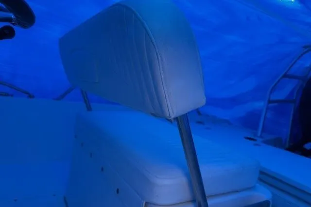 Slide: The Image of 2015 Boston Whaler 180 Dauntless boat interior with cushioned seating under blue cover. - 6