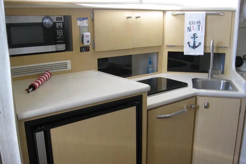 Slide: The Image of Compact kitchen in 2000 Bayliner 3055 Ciera Sunbridge, featuring microwave, sink, and stove. - 19